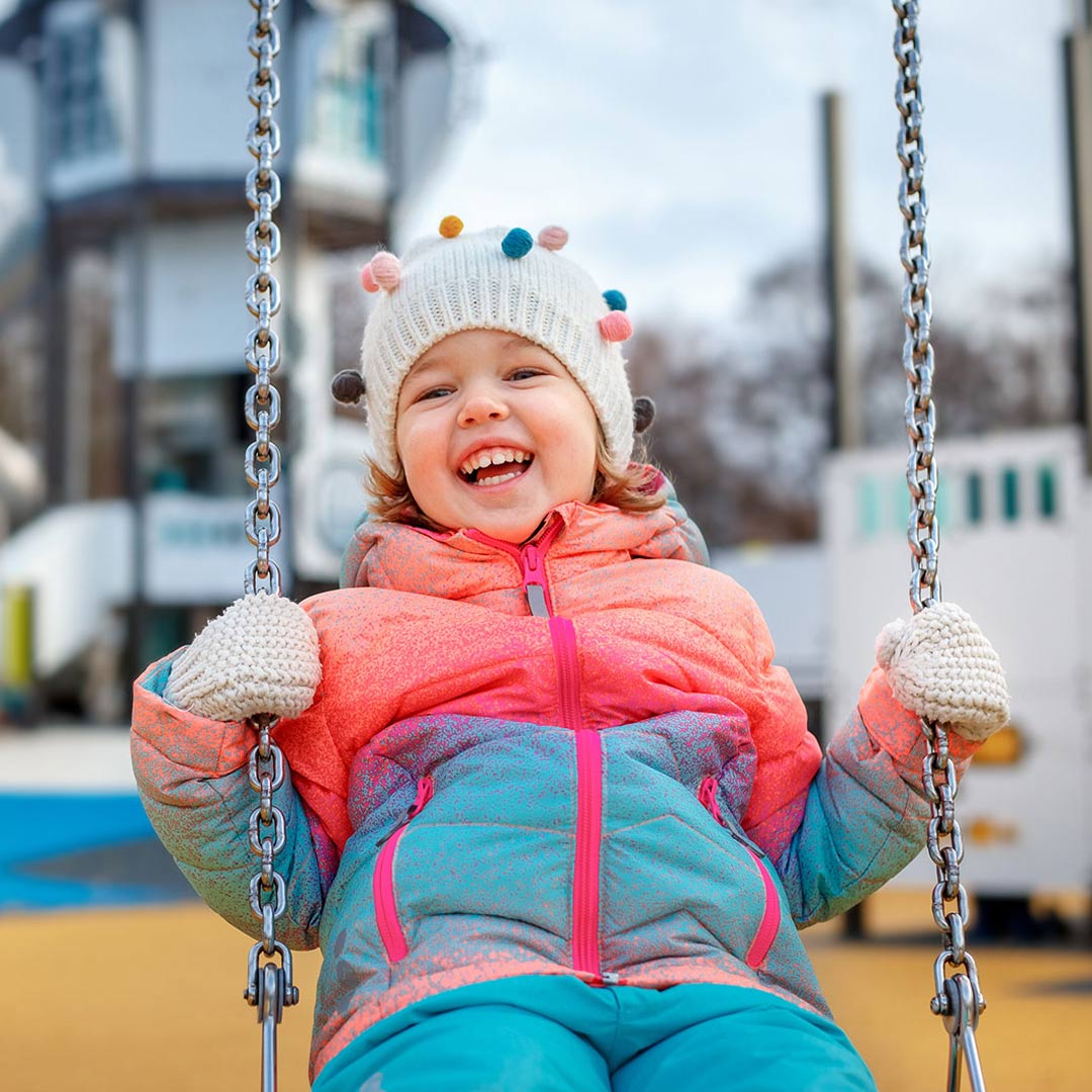 Little girl smiling while on a swing set