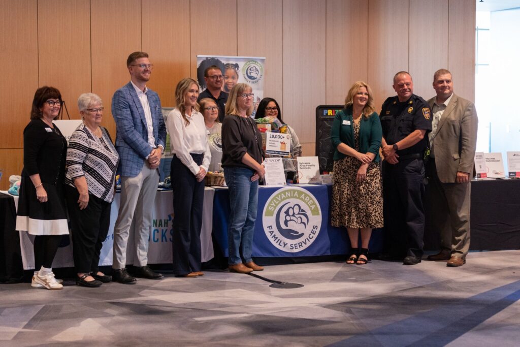 Group of IMPACT 2025 attendees posing together in front of nonprofit display boards