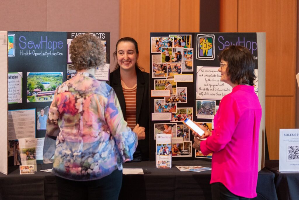 Attendees talking with a representative at the SewHope display board